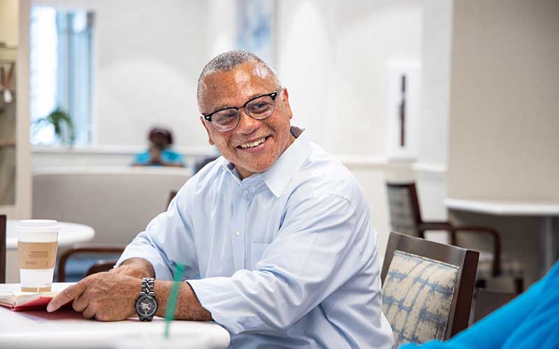 senior man reading a book while drinking coffee