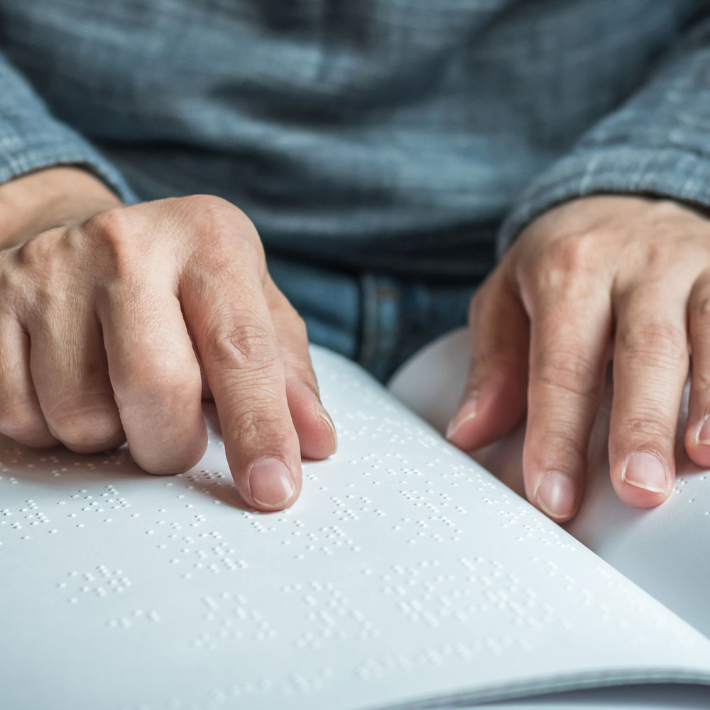 close-up of a senior man reading a page written in braille