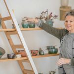 senior woman decorating her shelves with ceramic pots