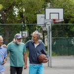 three senior men playing basketball together outside