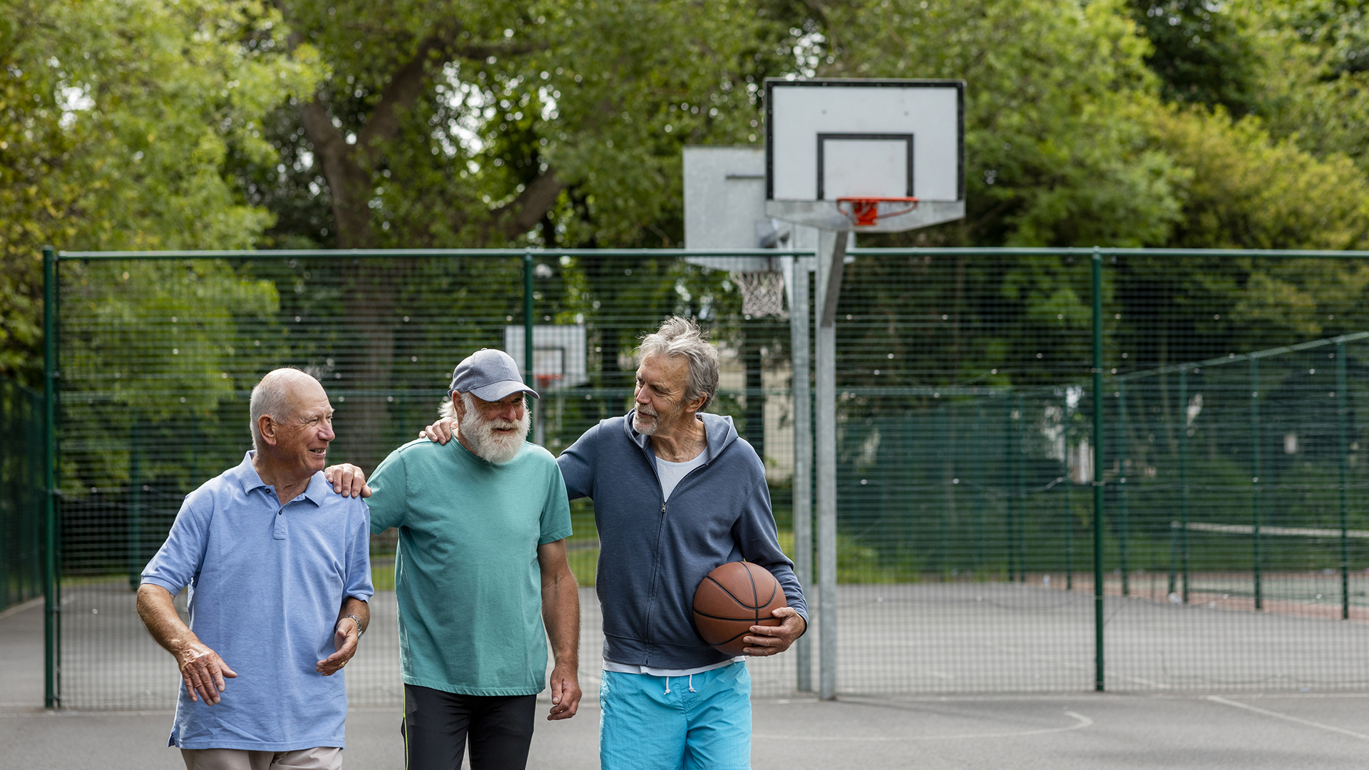 three senior men playing basketball together outside